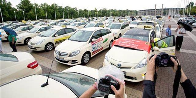 In this June 11, 2014, file photo, taxi drivers gather after a protest drive against the competition from Internet and mobile applications designed for calling cabs in Berlin.