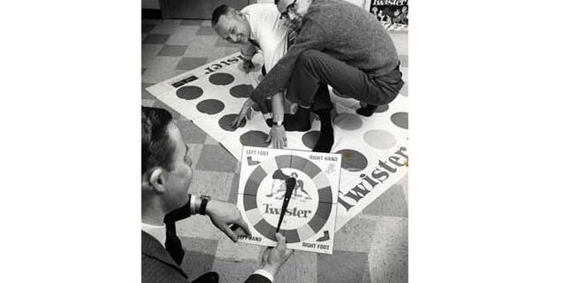 Dec. 16,1966: In this photo, co-inventors of the game "Twister" Charles Foley, left, and Neil Rabens demonstrate the game for Charles McCarty, foreground, president of Research and Development, Inc., in Minnesota.
