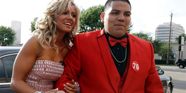 High school student Michael Ramirez, right, and Houston Texans cheerleader Caitlyn pose for pictures outside a restaurant before attending the prom Saturday, May 10, 2014, in Houston. Ramirez sent Caitlyn a Twitter message saying âIf I get 10,000 retweets will you go to prom with me (insert smiley face.) you will get asked in a cute way!â He did and so she said yes. (AP Photo/Pat Sullivan)