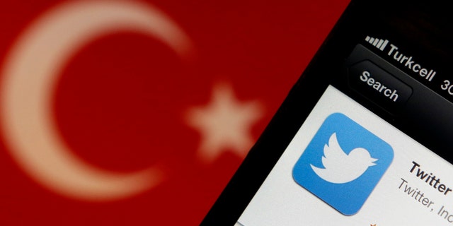 A Twitter logo on an iPhone display is pictured next to a Turkish flag in this photo illustration taken in Istanbul March 21, 2014.