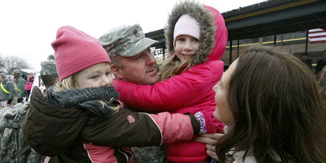 December 24, 2011: Sgt. Scott Dawson holds his daughters Mia, 5, left, and Victoria, 7, with his wife, Capt. Jessica Dawson, as U.S. Army 1st Cavalry 3rd Brigade soldiers return home from deployment in Iraq, on Christmas Eve at Fort Hood, Texas.