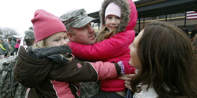 December 24, 2011: Sgt. Scott Dawson holds his daughters Mia, 5, left, and Victoria, 7, with his wife, Capt. Jessica Dawson, as U.S. Army 1st Cavalry 3rd Brigade soldiers return home from deployment in Iraq, on Christmas Eve at Fort Hood, Texas.