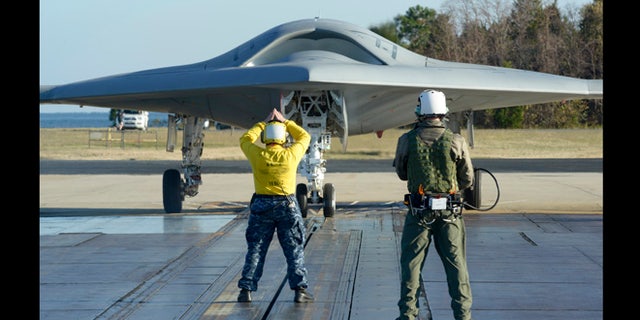 Nov. 29, 2012: In preparation for the first catapult launch of the U.S. Navy's X-47B unmanned aircraft, a flight deck director - aka "yellow shirt" - and a deck operator using Northrop Grumman's wireless, handheld Control Display Unit guide the aircraft into position on a shore-based catapult at Naval Air Station Patuxent River, Md.