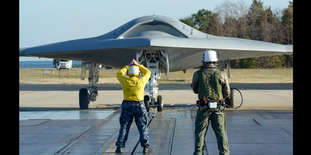 Nov. 29, 2012: In preparation for the first catapult launch of the U.S. Navy's X-47B unmanned aircraft, a flight deck director - aka "yellow shirt" - and a deck operator using Northrop Grumman's wireless, handheld Control Display Unit guide the aircraft into position on a shore-based catapult at Naval Air Station Patuxent River, Md.
