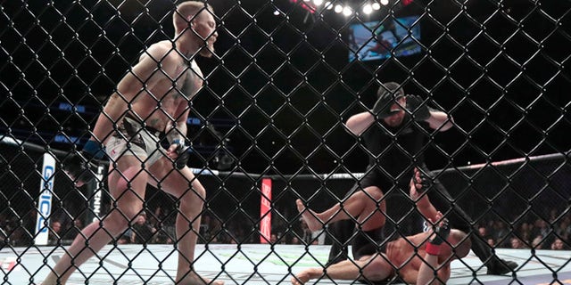Conor McGregor, left, reacts after the referee stopped his lightweight title mixed martial arts bout against Eddie Alvarez, bottom right, at UFC 205, early Sunday, Nov. 13, 2016, at Madison Square Garden in New York. (AP Photo/Julio Cortez)