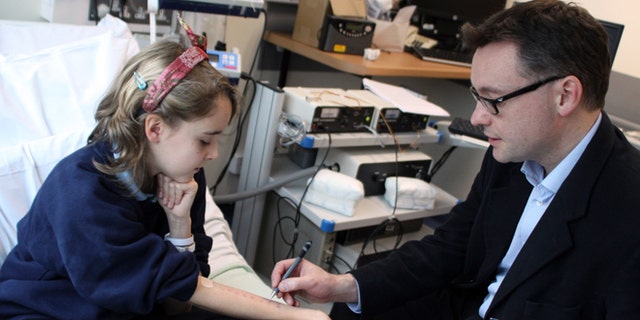 In this undated photo provided by Cambridge University Hospitals NHS Foundation Trust, Dr. Andrew Clark of Cambridge University, right, performs a skin prick test, which is used to diagnose food allergies, on Lena Barden, 12, during clinical trials at Addenbrooke's Hospital Clinical Research Facility, Cambridge, England. An experimental therapy in Britain that fed children with peanut allergies small amounts of peanut flour has helped more than 80 percent of them eat a handful of the previously worrisome nuts safely. Though experts say the results are encouraging, they warn it isnât something people should try at home. (AP Photo/Cambridge University Hospitals NHS Foundation Trust)