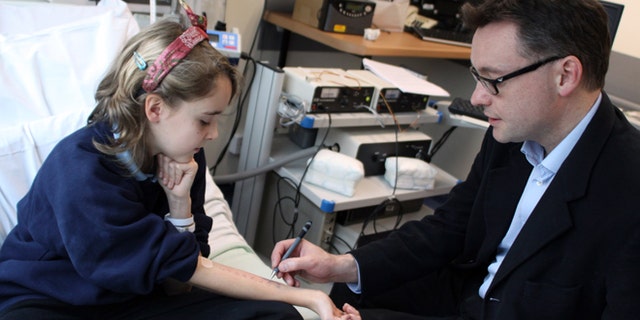 In this undated photo provided by Cambridge University Hospitals NHS Foundation Trust, Dr. Andrew Clark of Cambridge University, right, performs a skin prick test, which is used to diagnose food allergies, on Lena Barden, 12, during clinical trials at Addenbrooke's Hospital Clinical Research Facility, Cambridge, England. An experimental therapy in Britain that fed children with peanut allergies small amounts of peanut flour has helped more than 80 percent of them eat a handful of the previously worrisome nuts safely. Though experts say the results are encouraging, they warn it isnât something people should try at home. (AP Photo/Cambridge University Hospitals NHS Foundation Trust)
