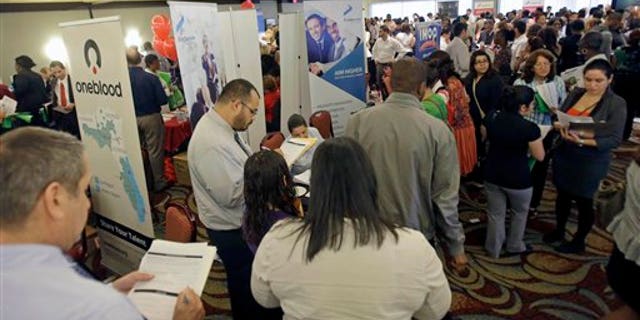 FILE - This Aug. 14, 2013 file photo shows job seekers checking out companies at a job fair in Miami Lakes, Fla. More than 1 million Americans are bracing for a harrowing, post-Christmas jolt as federal unemployment benefits come to a sudden halt this weekend. The development entails potentially significant implications for the recovering U.S. economy and sets up a tense battle when Congress reconvenes in the new year. (AP Photo/Alan Diaz, File)
