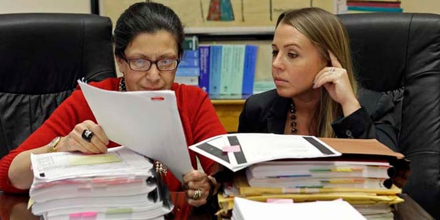 Attorneys Grisel Ybarra and Monica Barba Neumann look over documents at their office in Miami, on July 16, 2015.