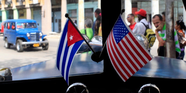 FILE - In this March 22, 2013 file photo, miniature flags representing Cuba and the U.S. are displayed on the dash of an American classic car in Havana, Cuba. The Obama administration is putting a large dent in the U.S. embargo against Cuba as of Friday, significantly loosening restrictions on American trade and investment. The new rules also open up the communist island to greater American travel and allow U.S. citizens to start bringing home small amounts of Cuban cigars after more than a half-century ban. (AP Photo/Franklin Reyes, File)