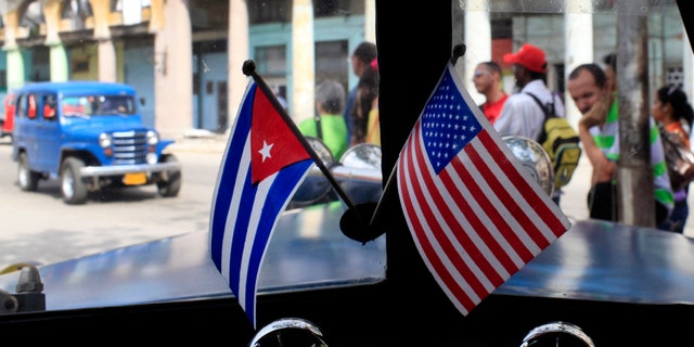FILE - In this March 22, 2013 file photo, miniature flags representing Cuba and the U.S. are displayed on the dash of an American classic car in Havana, Cuba. The Obama administration is putting a large dent in the U.S. embargo against Cuba as of Friday, significantly loosening restrictions on American trade and investment. The new rules also open up the communist island to greater American travel and allow U.S. citizens to start bringing home small amounts of Cuban cigars after more than a half-century ban. (AP Photo/Franklin Reyes, File)