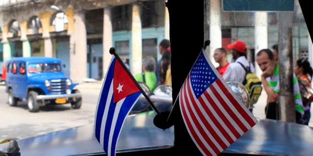 This March 22, 2013 file photo shows miniature flags representing Cuba and the U.S. displayed on the dash of an American classic car in Havana, Cuba.