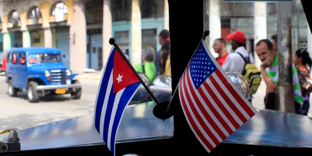 This March 22, 2013 file photo shows miniature flags representing Cuba and the U.S. displayed on the dash of an American classic car in Havana, Cuba.