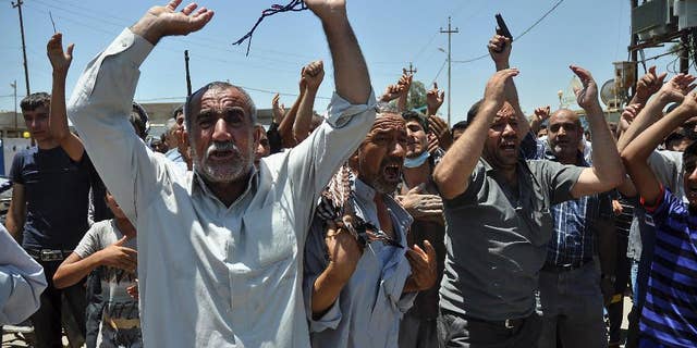 In this June 23, 2014, photo, mourners chant slogans against the al-Qaida breakaway group Islamic State of Iraq and the Levant after they bury 15 bodies in the village of Taza Khormato near the northern oil-rich city of Kirkuk, Iraq. U.S. teams of special forces going into Iraq after a three-year gap will face an aggressive insurgency, a splintering military and a precarious political situation as they help Iraqi security forces improve their ability to battle Sunni militants. (AP Photo/Emad Matti)