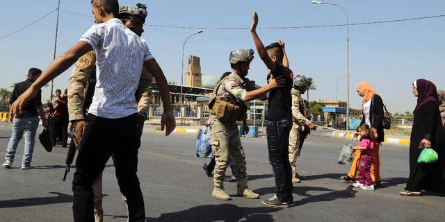 FILE - In this Oct. 6, 2014, file photo, Army soldiers search Iraqis amid tight security during Eid al-Adha celebrations in Baghdad, Iraq. Iraq’s fractured army has begun to regroup and stage modest, localized attacks on the Islamic State militants who routed them last spring and summer, but they are unlikely to be ready to launch a major counteroffensive for many months, senior U.S. military officials said Thursday. (AP Photo/Karim Kadim, File)