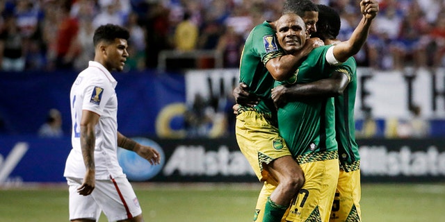 Jamaicas Rudolph Austin, facing camera, celebrates with teammates Joel McAnuff, left, and Je-Vaughn Watson, right, as United States DeAndre Yedlin walks off the pitch after Jamaica defeated the United States 2-1 in a CONCACAF Gold Cup soccer semifinal Wednesday, July 22, 2015, in Atlanta. (AP Photo/David Goldman)