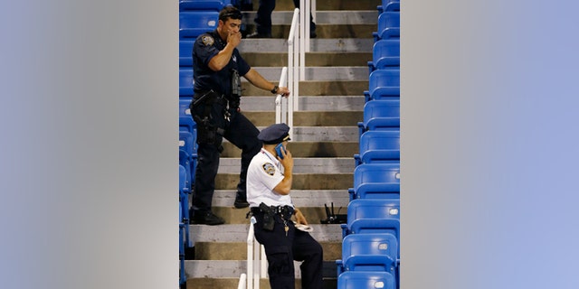 Sept. 3, 2015: Police officers investigate the southwest corner of Louis Armstrong Stadium after a drone flew over the court, buzzing the players during a match between Flavia Pennetta and Monica Niculescu during the second round of the U.S. Open tennis tournament in New York. The drone crashed into the seats and can be seen to the right of the police officer on his phone. (AP Photo/Kathy Willens)
