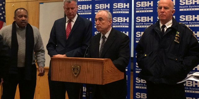 New York City Mayor Bill de Blasio, second left, stands by as Police Commissioner William Bratton, second right, speaks at a news conference at St. Barnabas Hospital in the Bronx section of New York City after two New York City police officers were shot. The two officers responding to a robbery in the Bronx were shot and wounded Monday night, and a manhunt was underway for at least two suspects, authorities said. The officers were taken to the hospital with non-life threatening injuries. (AP Photo/Tom McElroy)