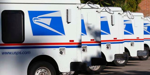 In this Nov. 13, 2013 file photo U.S. postal service trucks sit parked at the post office in Del Mar, California.