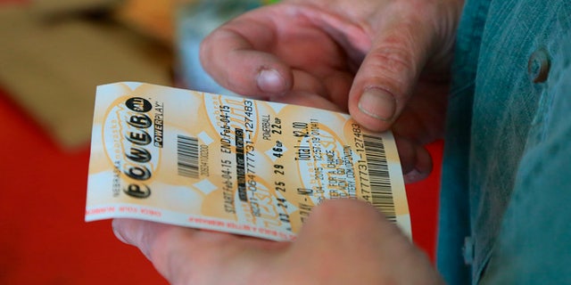Feb. 4, 2015: A customer inspects the Powerball ticket she purchased at a U-Stop store in Lincoln, Neb.