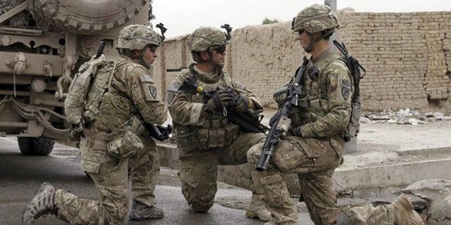 U.S. Army soldiers speak among themselves near a suicide bomb blast site in Kandahar April 14, 2011. A suicide bomber wounded three civilians, including two women, when he detonated his explosives before reaching the target of his attack in southern Kandahar province, said Khan Mohammad Mujahid, a senior Kandahar police official. REUTERS/Ahmad Nadeem (AFGHANISTAN - Tags: CIVIL UNREST MILITARY CRIME LAW)