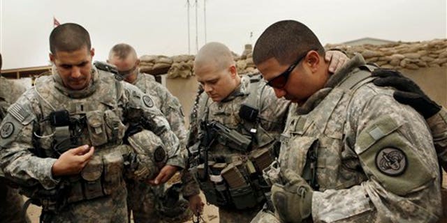 Army Lt. Daniel McCord, left, Staff Sgt. Marc Krugh, center, and Sgt. Christopher Torrentes, from the 3rd Armored Cavalry Regiment pray before heading out on a patrol at Contingency Operating Site Kalsu, south of Baghdad, Iraq.