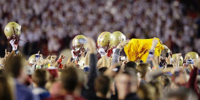 Celebrating members of the Boston College team, holding their helmets above their heads, are surrounded by celebrating fans after they defeated Southern California in their NCAA college football game Saturday, Sept. 13, 2014 in Boston. Boston College defeated USC 37-3. (AP Photo/Stephan Savoia)