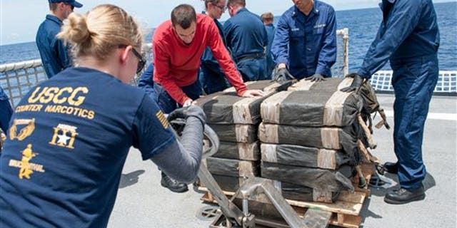 In this July 19, 2015 photo released by the U.S. Coast Guard, Coast Guard Cutter Stratton crew members secure cocaine bale from a self-propelled semi-submersible in international waters off the coast of Central America. The seizure of around 12,000 pounds was one of the largest busts of its kind.
