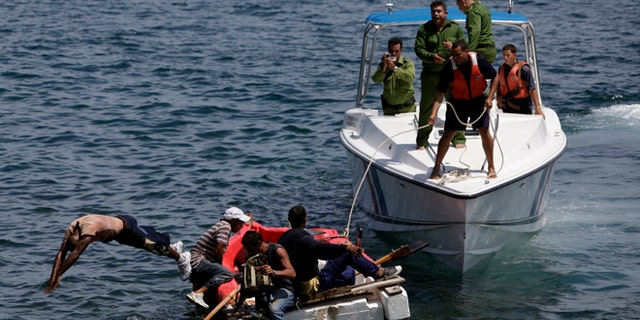 In this June 4, 2009 file photo, Cuban coast guards, right, stop seven men trying to migrate illegally to the U.S. on a foam raft near Havana's Malecon. No one was arrested, according to police.