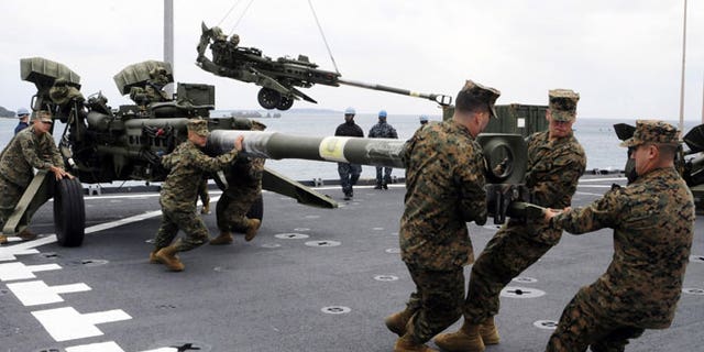 In this Feb. 2, 2012 file photo released by U.S. Navy, U.S. Marines assigned to the 31st Marine Expeditionary Unit haul a 155 mm Howitzer onto the flight deck of the forward-deployed amphibious dock landing ship USS Germantown in Okinawa, Japan, when the ship pulled into Okinawa to embark the Marines in preparation of exercise Cobra Gold 2012.
