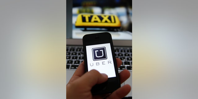 An illustration picture shows the Uber logo on a smartphone next to the picture of an official German taxi sign in Frankfurt, Sep. 15, 2014.