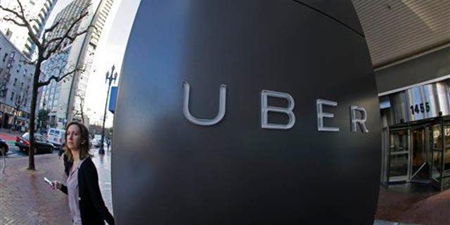 In this photo taken Tuesday, Dec. 16, 2014, a woman leaves the headquarters of Uber in San Francisco.