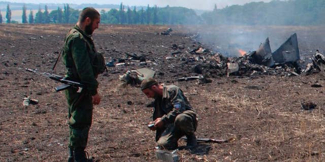 In this framegrab made from a video provided by press service of the rebel Donetsk People's Republic and icorpus.ru, pro-Russians collect parts of the burning debris of a Ukrainian military fighter jet, shot down at Savur Mogila, eastern Ukraine, Wednesday, July 23, 2014. Two Ukrainian military Sukhoi-25 fighters have been shot down in the east, according to the country's Defense Ministry. (AP Photo/icorpus.ru, Press Service of the rebel Donetsk People's Republic)