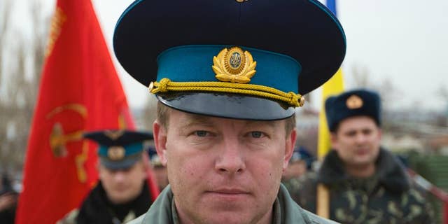 FILE - In this Tuesday, March 4, 2014 file photo, Air Force Col. Yuliy Mamchur, commander of the Ukrainian Belbek Air Base, leads his men to the base outside Sevastopol, Ukraine. The day after Crimeans voted to leave Ukraine and join Russia, a man in a black raincoat turned up at the gate of the Belbek Air Base to demand that the Ukrainian forces holed up inside surrender to Russia. The Ukrainian commander of the base came out proudly wearing his visor cap decorated with gold wings - and refused. Having withstood five days of sustained intimidation and pressure to defect from his captors, Mamchur now awaits a hero’s welcome in the capital, Kiev. (AP Photo/Ivan Sekretarev, File)
