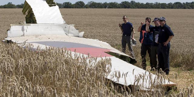 FILE - This Aug. 1, 2014 file photo shows investigators examining a piece of the Malaysia Airlines Flight 17 plane crash near the village of Hrabove, Donetsk region, eastern Ukraine. U.S. and international pilot unions are pressing the Obama administration and global aviation officials to get intelligence to airlines faster on potential threats to civil aviation from hostilities around the world following last month’s shoot down of an airliner carrying nearly 300 people. (AP Photo/Dmitry Lovetsky, File)