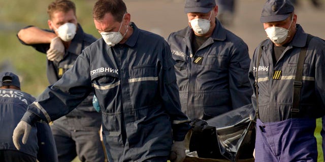 July 19, 2014: Emergency workers carry the body of a victim at the crash site of Malaysia Airlines Flight 17 near the village of Hrabove, eastern Ukraine. (AP Photo/Vadim Ghirda)