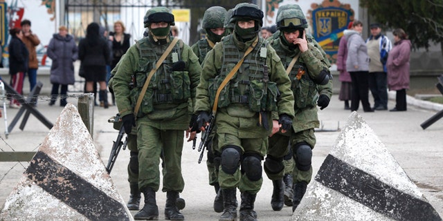 Pro Russian soldiers guard Ukraine's infantry base in Perevalne, Ukraine, Tuesday, March 4, 2014. Russian President Vladimir Putin said Moscow reserves the right to use all means to protect Russians in Ukraine as U.S. Secretary of State John Kerry was on his way to Kiev. Tensions remained high in the strategic Ukrainian peninsula of Crimea with troops loyal to Moscow firing warning shots to ward off protesting Ukrainian soldiers. (AP Photo/Sergei Grits)