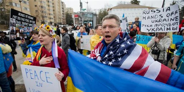 Moscow-born Dmitry Savransky, right, who holds dual citizenship, American and Russian, joins his Ukrainian wife Natalya Seay, left, during a protest rally in front of the Russian embassy, in Washington, Sunday, March 2, 2014. Igniting a tense standoff, Russian forces surrounded a Ukrainian army base Sunday just as the country began mobilizing in response to the surprise Russian takeover of Crimea. Outrage over Russia's tactics mounted in world capitals, with U.S. Secretary of State John Kerry calling on President Vladimir Putin to pull back from "an incredible act of aggression." (AP Photo/Manuel Balce Ceneta)