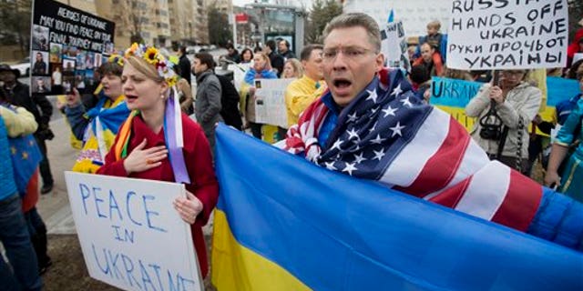 Moscow-born Dmitry Savransky, right, who holds dual citizenship, American and Russian, joins his Ukrainian wife Natalya Seay, left, during a protest rally in front of the Russian embassy, in Washington, Sunday, March 2, 2014. Igniting a tense standoff, Russian forces surrounded a Ukrainian army base Sunday just as the country began mobilizing in response to the surprise Russian takeover of Crimea. Outrage over Russia's tactics mounted in world capitals, with U.S. Secretary of State John Kerry calling on President Vladimir Putin to pull back from "an incredible act of aggression." (AP Photo/Manuel Balce Ceneta)