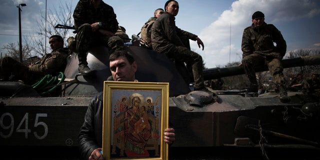April 16, 2014: A local resident holds an Orthodox icon in front of an armored vehicle and soldiers of the Ukrainian Army, as they are blocked by people on their way to the town of Kramatorsk. Pro-Russian insurgents commandeered six Ukrainian armored vehicles along with their crews and hoisted Russian flags over them Wednesday, dampening the central government's hopes of re-establishing control over restive eastern Ukraine. (AP Photo/Manu Brabo)