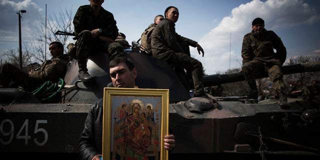 April 16, 2014: A local resident holds an Orthodox icon in front of an armored vehicle and soldiers of the Ukrainian Army, as they are blocked by people on their way to the town of Kramatorsk. Pro-Russian insurgents commandeered six Ukrainian armored vehicles along with their crews and hoisted Russian flags over them Wednesday, dampening the central government's hopes of re-establishing control over restive eastern Ukraine. (AP Photo/Manu Brabo)