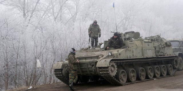 Feb. 15, 2015: Ukrainian government soldiers rest by armored vehicle on the road between the towns of Dabeltseve and Artemivsk. (AP Photo/Petr David Josek)