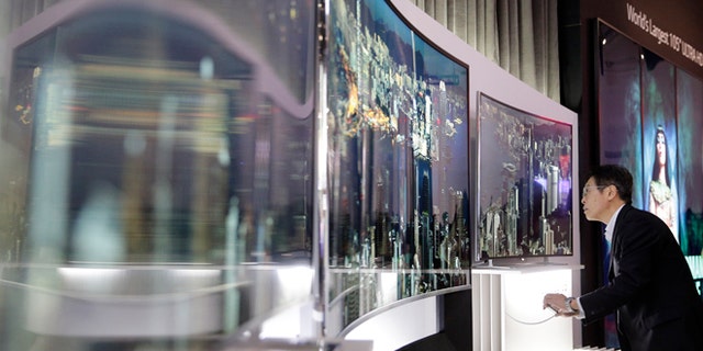 A show attendee looks at LG's 105-inch curved ultra HD TV at the International Consumer Electronics Show(CES) on Tuesday, Jan. 7, 2014, in Las Vegas. (AP Photo/Jae C. Hong)