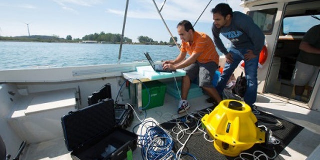 Doctoral candidates with the University of Buffalo drop two 40-pound sensors into the water to test out an "underwater Internet" using sonar rather than radio waves.