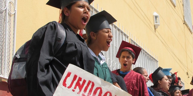 FILE - In this Sept. 20, 2013 file photo, wearing graduation-style caps and gowns, Mexican youth raised in the U.S, chant slogans outside a migrant shelter before crossing the international bridge from Nuevo Laredo, Mexico. A lawyer who traveled to the Texas-Mexico border with the 34 immigrants protesting U.S. immigration policies says 25 of the 26 remaining in federal custody have completed another step in their requests for asylum. (AP Photo/Christopher Sherman, File)