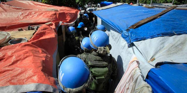 FILE - In this Tuesday, March 30, 2010 file photo, United Nations peacekeepers patrol an earthquake survivors makeshift camp in Port-au-Prince. In 2015, troubled by peacekeepers' sexual relationships with the people they are meant to protect, the UN has quietly started helping with DNA collection to prove paternity claims for so-called "peacekeeper babies." (AP Photo/Jorge Saenz)