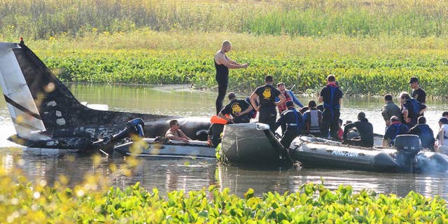 Rescue personnel work to recover remains from the wreckage of a crashed aircraft at Laguna del Sauce, near Punta del Este, Uruguay, Friday, March 20, 2015. Uruguay's Air Force says the Argentine turboprop airplane crashed and burned Thursday, shortly after taking off, killing all aboard. (AP Photo/Marcelo Rodriguez)