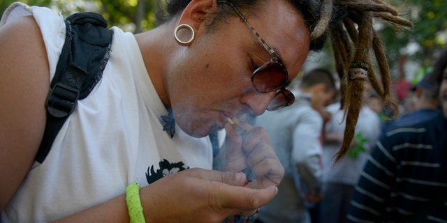 A man smokes a marijuana cigarette during a demonstration in support of the legalization of marijuana outside the Congress in Montevideo, Uruguay, Tuesday, Dec. 10, 2013. Uruguay's Senate was finishing its final debate Tuesday before voting on a plan to create the world's first national marijuana market, with the state regulating the entire process of growing, selling and using a drug that is illegal almost everywhere else. (AP Photo/Matilde Campodonico)