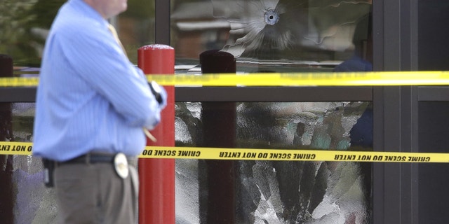 April 29, 2013: A West Valley City Police Officer stands near a bullet shattered window at the West Valley City Police Department in West Valley City, Utah.