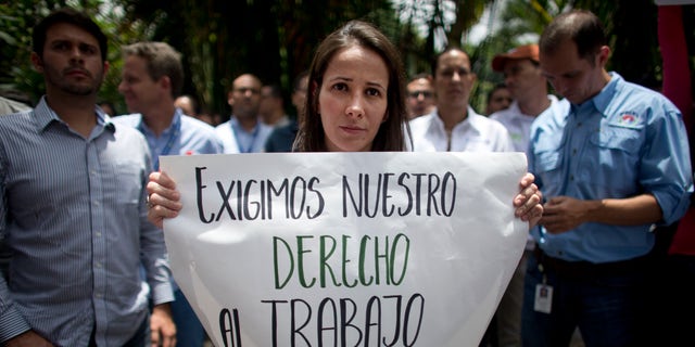 A Polar worker holds a sign that reads in Spanish: "We demand our right to work. Raw material now!" during a protest by workers who fear losing their jobs, outside company headquarters in Caracas, Venezuela, Friday, April 22, 2016. Polar, the largest producer of beer in the country, said Thursday the lack of imported raw materials could force them to stop producing beer starting April 29, when their current stock of malted barley would run out. (AP Photo/Ariana Cubillos)